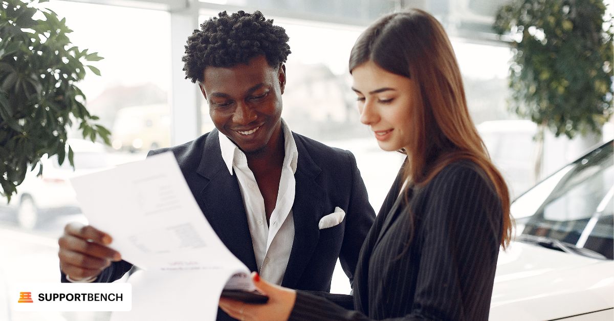 A man and woman sit at a table with a laptop, engaged in a conversation about help desk solutions