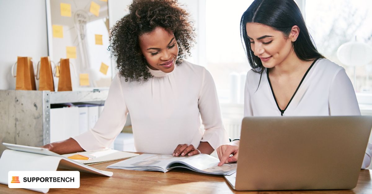 Two colleagues seated at a table with a laptop, engaged in a discussion about modern escalation management