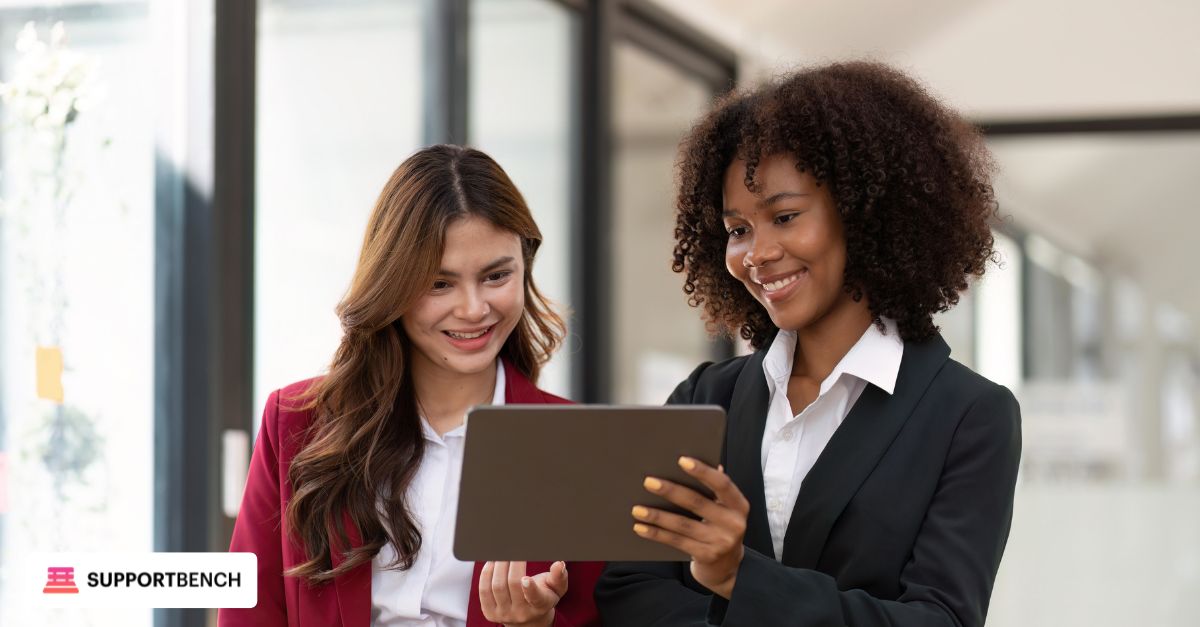 A manager and helpdesk agent discussing feedback charts and improvement plans on a tablet