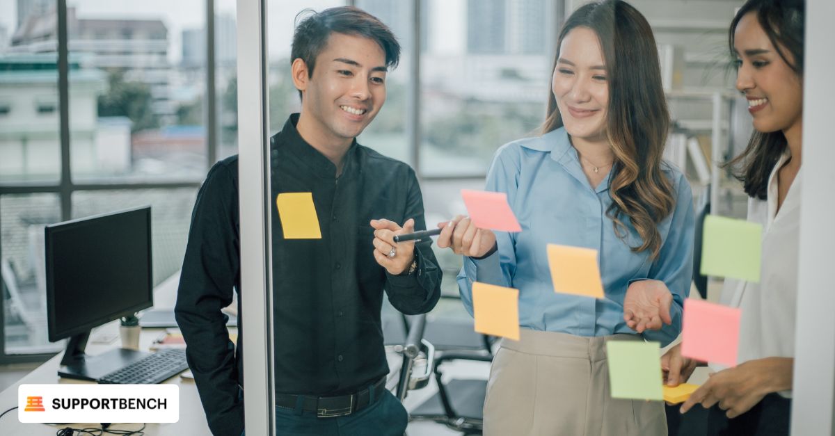 A team stand before a wall filled with colorful sticky notes, discussing customer prioritization and segmentation strategies